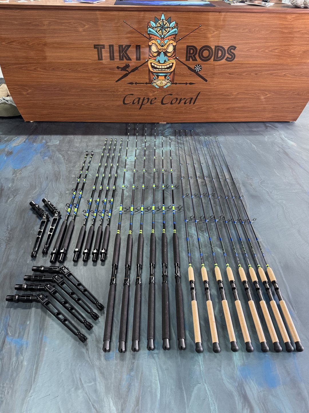 A carved Tiki Rods Cape Coral sign above a full set of finished rods laid out across the marbled work table